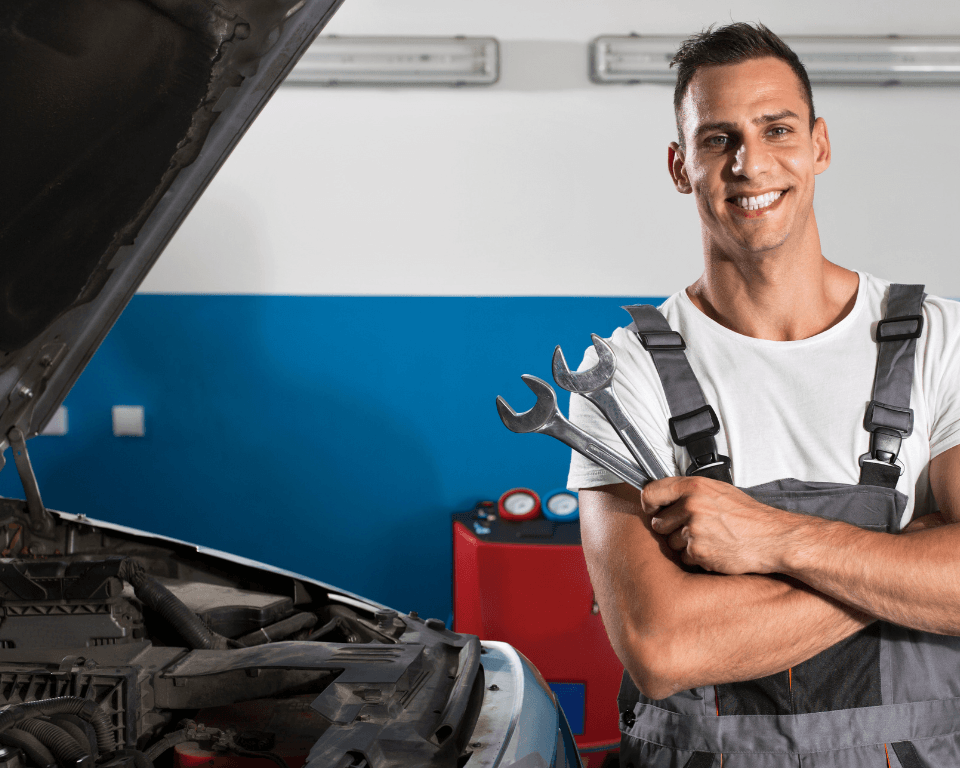 a smiling mechanic holding wrenches