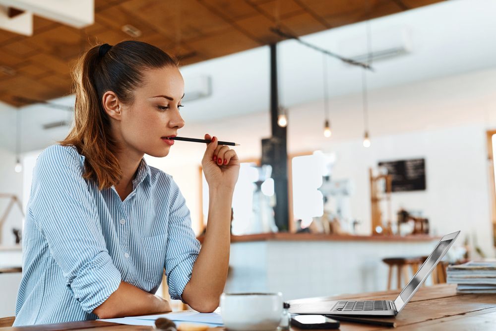 A Woman is Sitting at a Table With a Laptop and a Cup of Coffee — Successful Resumes in Mackay, QLD