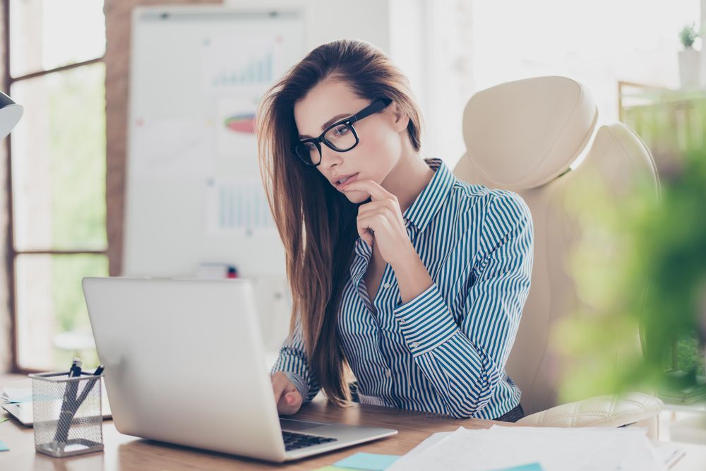 A Woman is Sitting at a Desk Using a Laptop Computer — Successful Resumes in Bundaberg, QLD