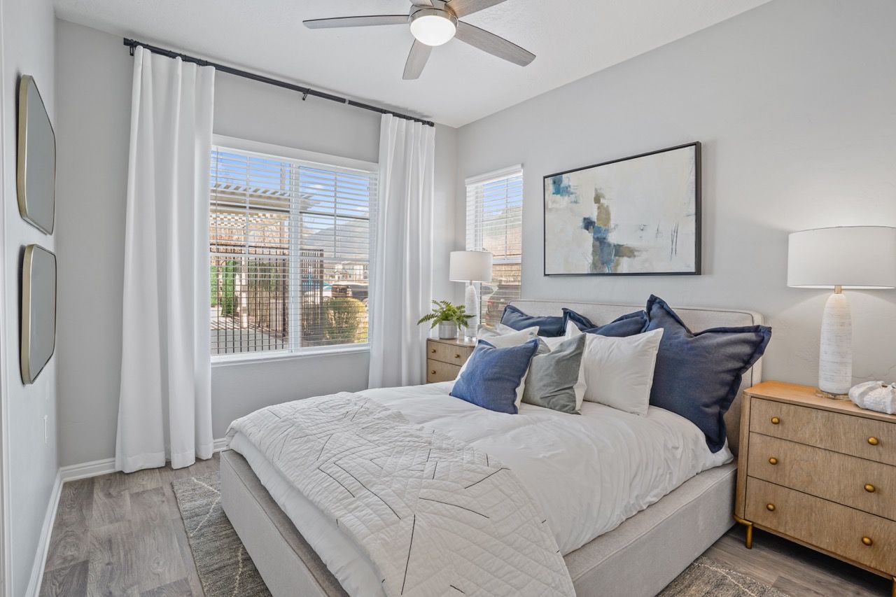 Bright bedroom with a large bed, white curtains, two wooden nightstands, and abstract wall art.