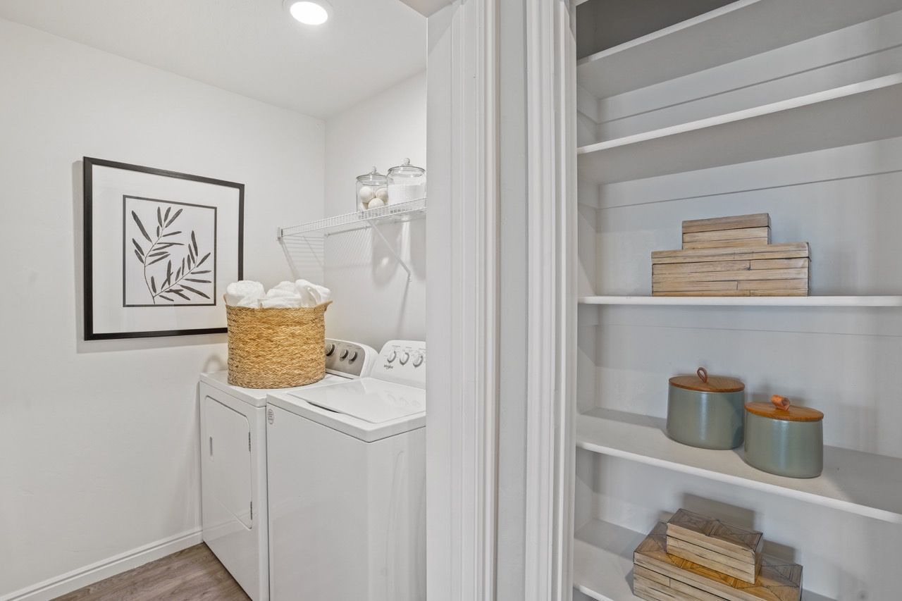 Laundry room with a washer and dryer, shelving, and woven storage baskets.