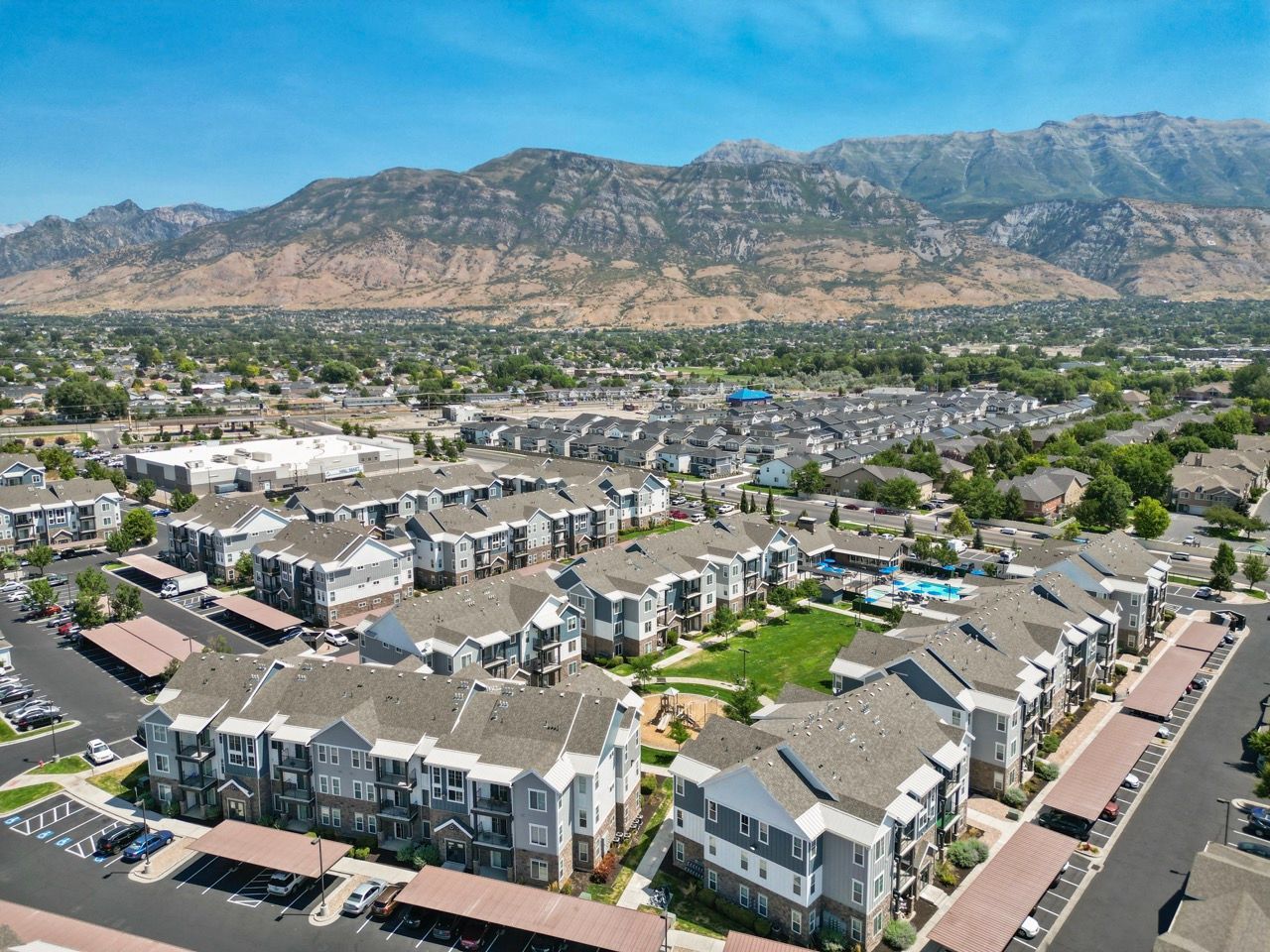 Aerial view of a large apartment community with many buildings, parking lots, and distant mountains.