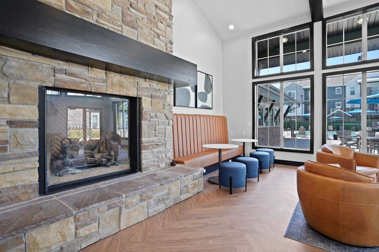 Community lounge with a stone fireplace, leather seating, and large windows overlooking the pool.