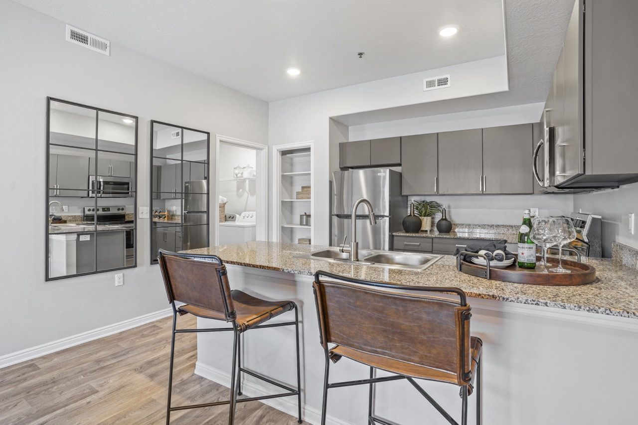 Modern apartment kitchen with granite island, double sink, and stainless steel appliances.