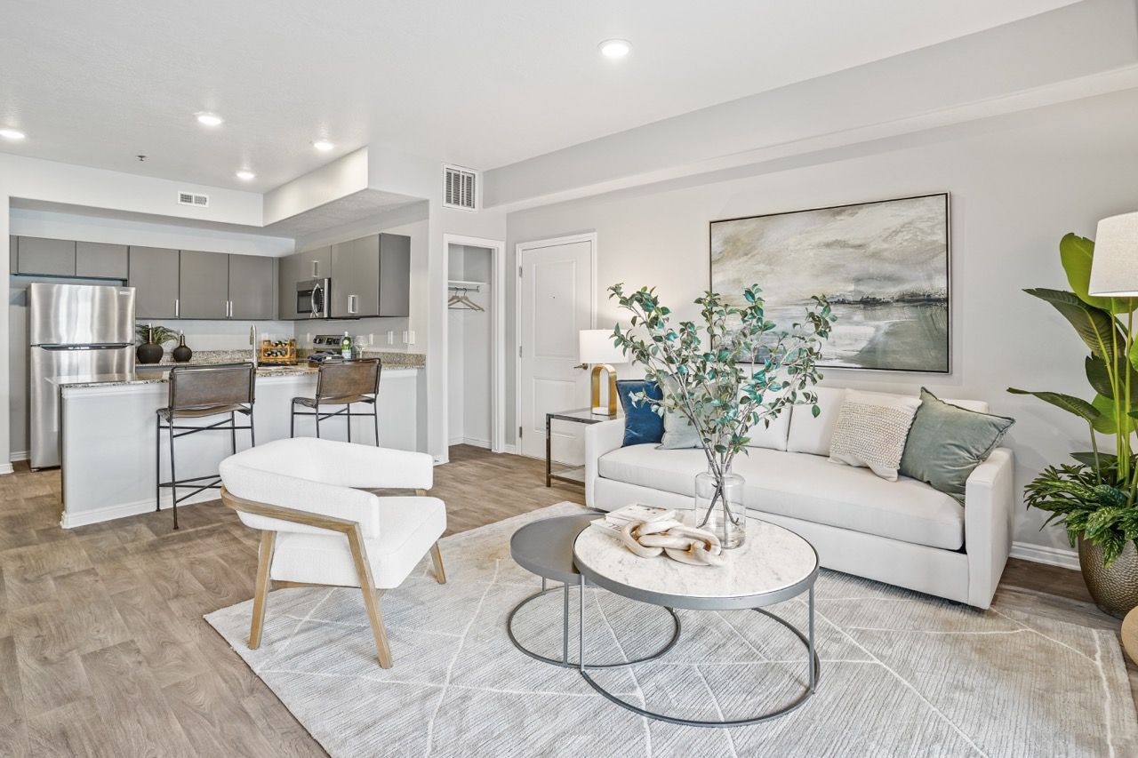Open-concept living room with white sofa, chair, coffee table, and a modern kitchen in the background.