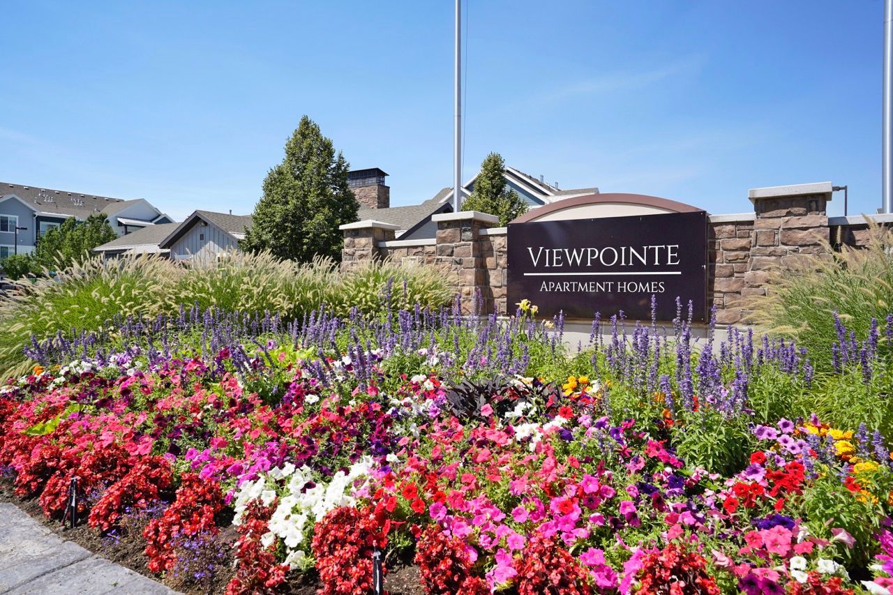 Exterior sign for View Pointe Apartment Homes with a colorful flower bed.