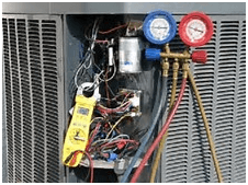 HVAC unit being serviced. A technician is using gauges and a clamp meter to measure pressure and electricity.