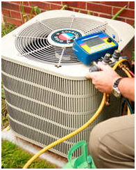 HVAC technician servicing an air conditioner unit. Yellow hose connected, gauge display. Outdoors, grass setting.
