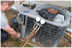 Man working on an air conditioning unit outdoors, using gauges and tools.
