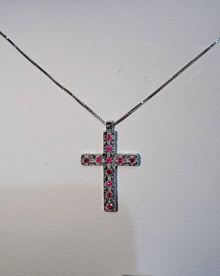 Collana con ciondolo a croce in argento e pietre preziose rosse.