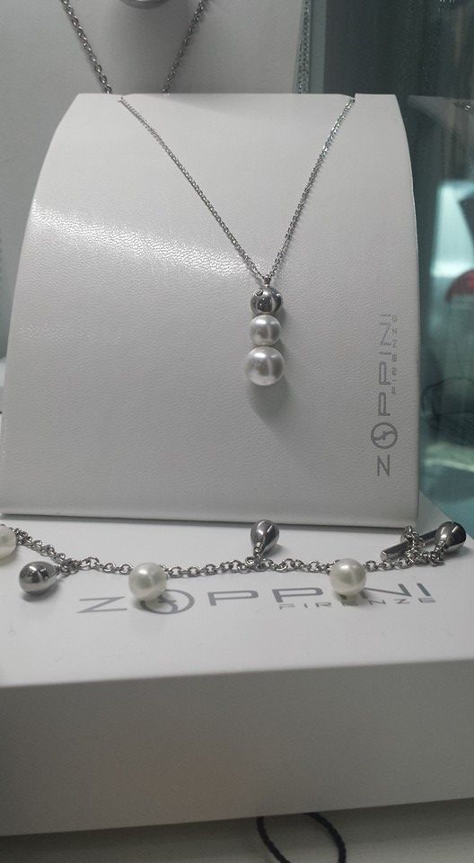 Collana e bracciale con perle esposti su supporti bianchi, all'interno di una vetrina.