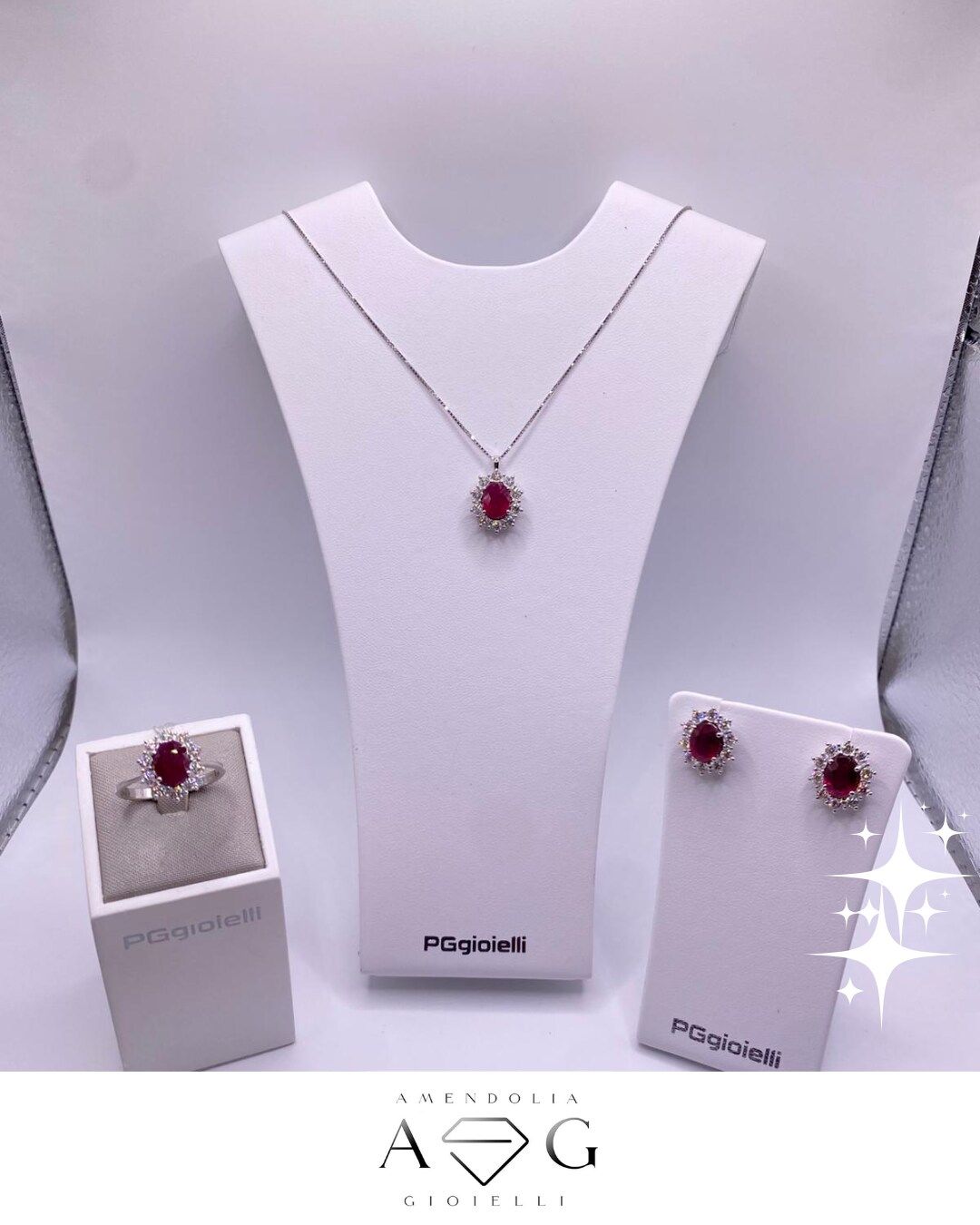 Parure di gioielli con pietre di rubino: anello, collana e orecchini su espositori bianchi.