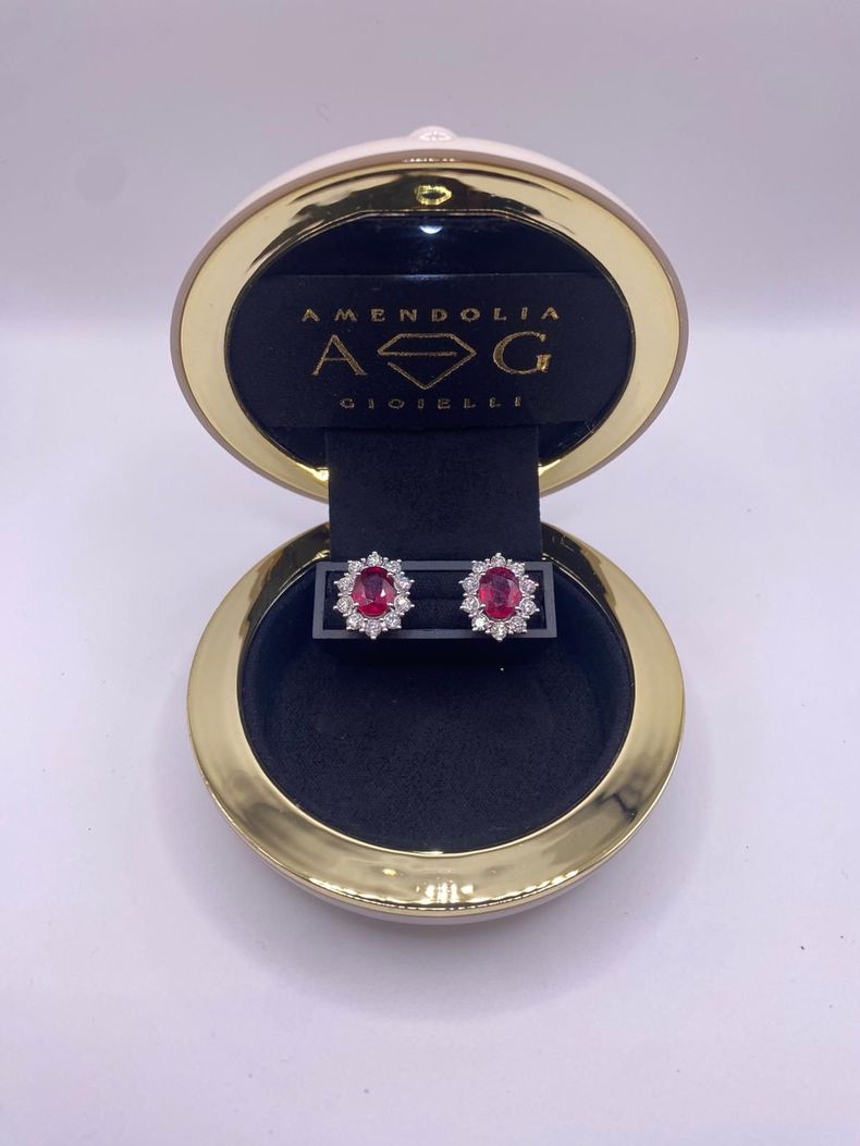 Orecchini a bottone con diamanti su velluto grigio all'interno di un portagioie; sfondo blu.