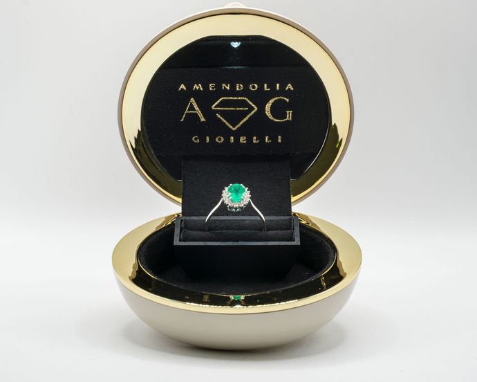 Anello con smeraldo in una scatola portagioie dorata e nera.