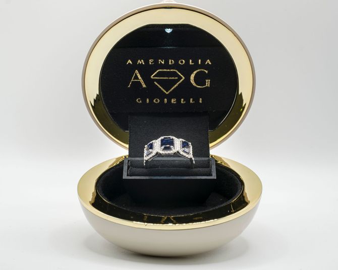 Anello in un portagioie d'oro aperto, su un espositore di velluto nero.