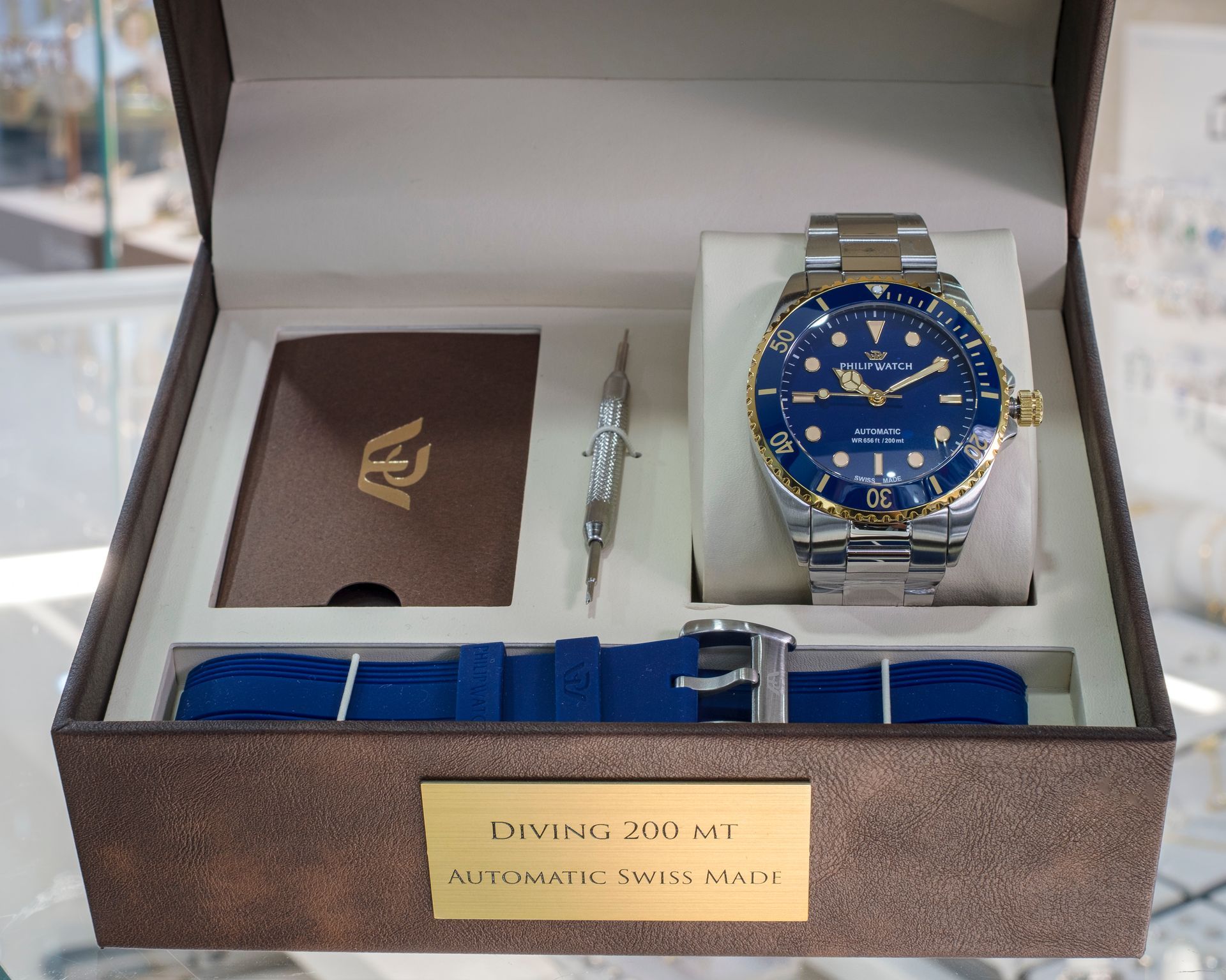 Set di orologi in una scatola: orologio blu e argento, cinturino blu, attrezzo e marchio.