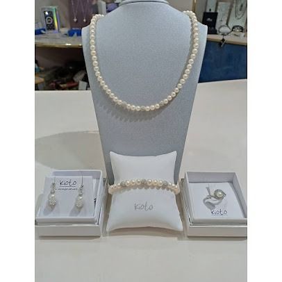 Collana di perle, bracciale e orecchini esposti su supporti bianchi, inseriti in scatole.