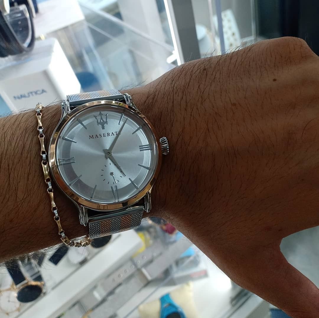 Polso di una persona con un orologio in argento e oro e un bracciale in oro. Il quadrante dell'orologio presenta dettagli in argento e oro.