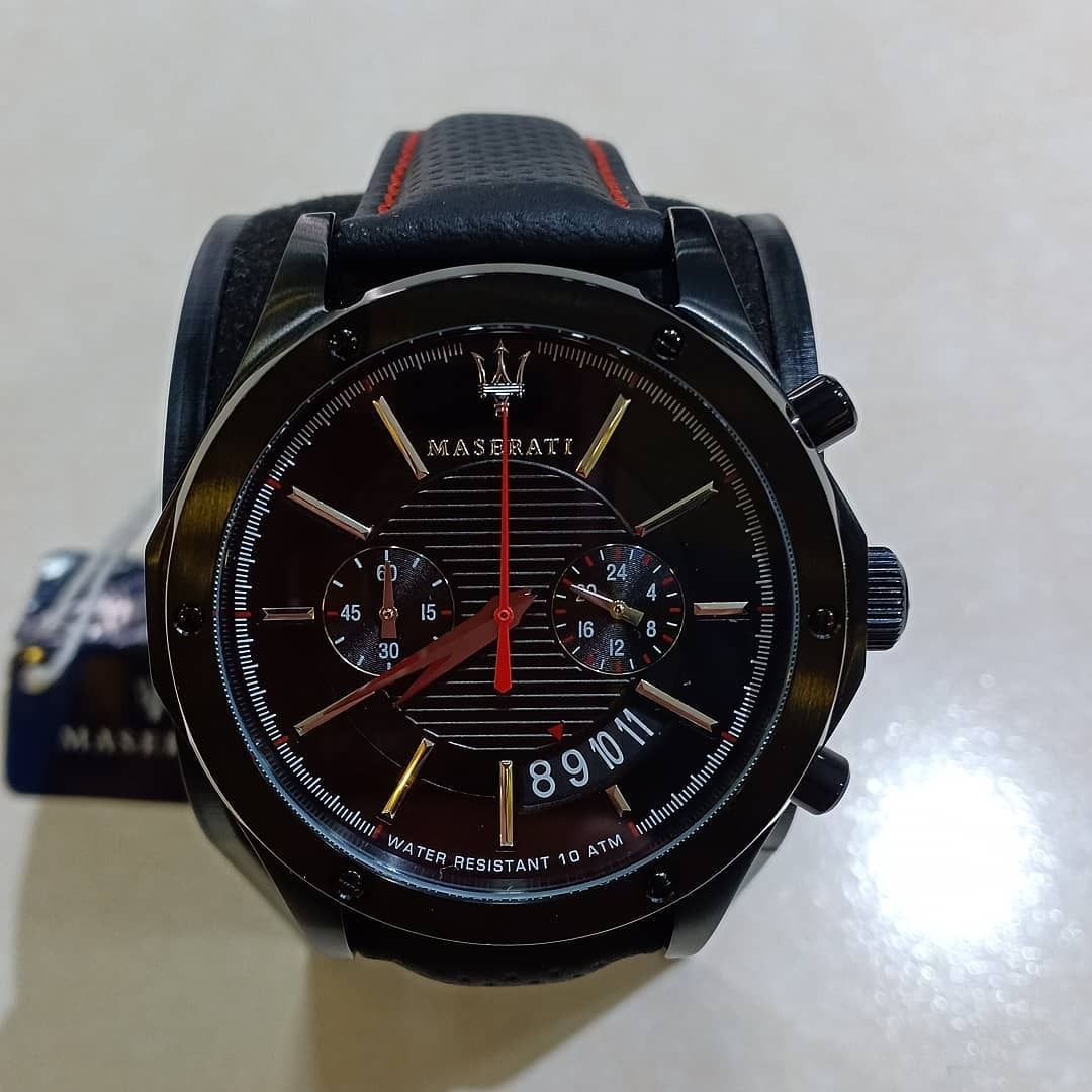 Orologio Maserati nero con cinturino nero, quadrante nero e lancette dorate su una superficie chiara.