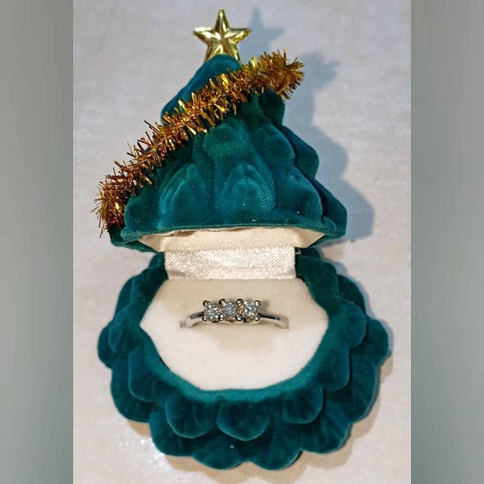 Anello all'interno di una scatola di velluto verde acqua a forma di albero di Natale con stella dorata in cima e ghirlanda.