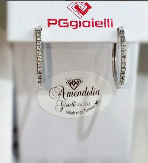 Orecchini a cerchio con diamanti esposti su un espositore bianco. Insegna della gioielleria: Amendolia.