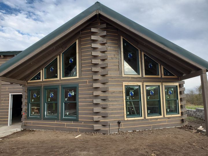 A wooden house with a green roof and lots of windows