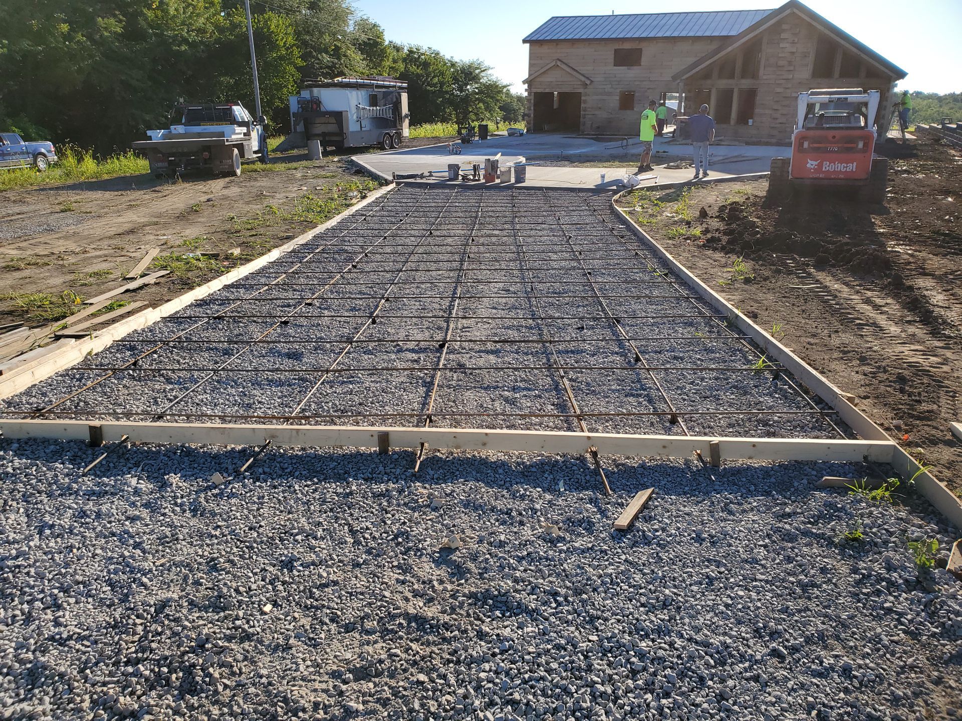 A gravel driveway is being built in front of a house.