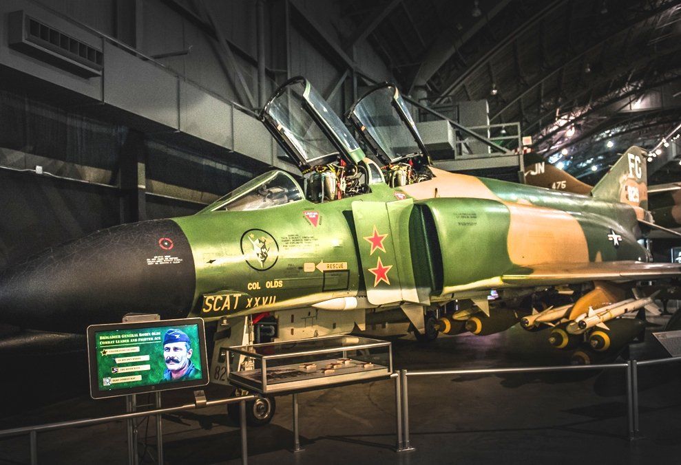 A green fighter jet is on display in a museum.