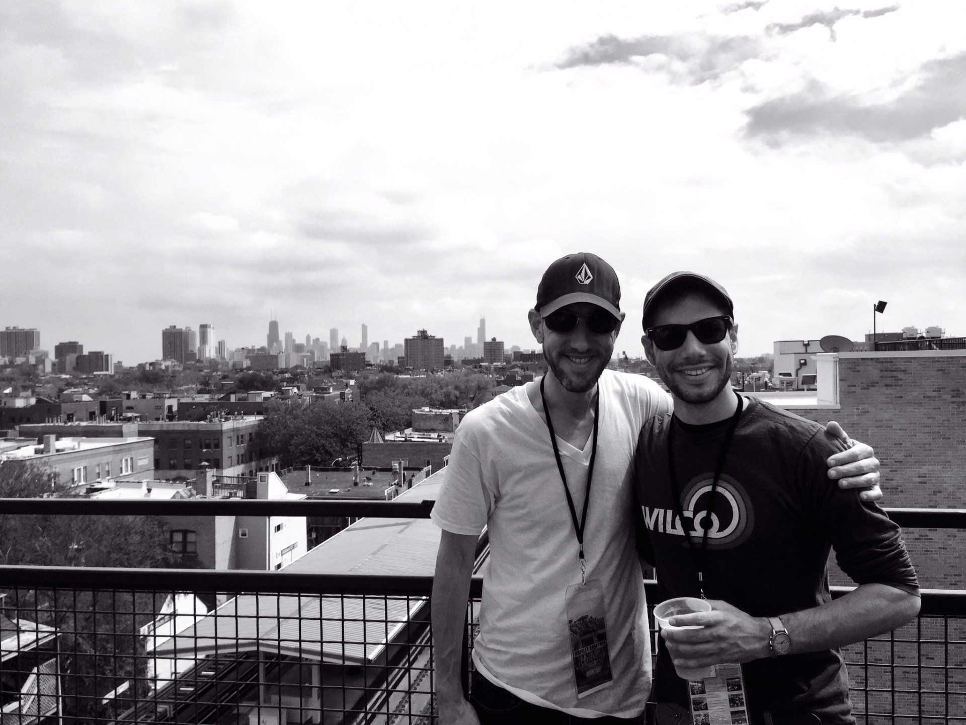 Two men are standing next to each other in front of a city skyline.
