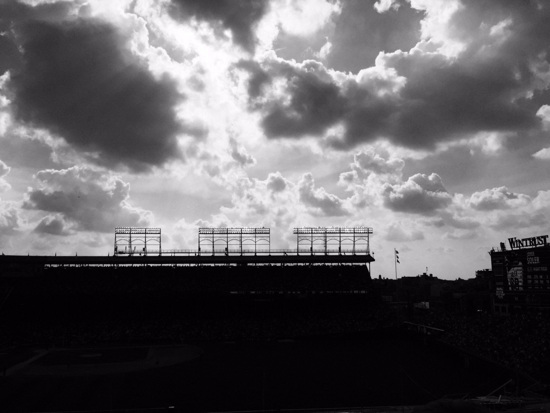 A black and white photo of a building under construction against a cloudy sky.