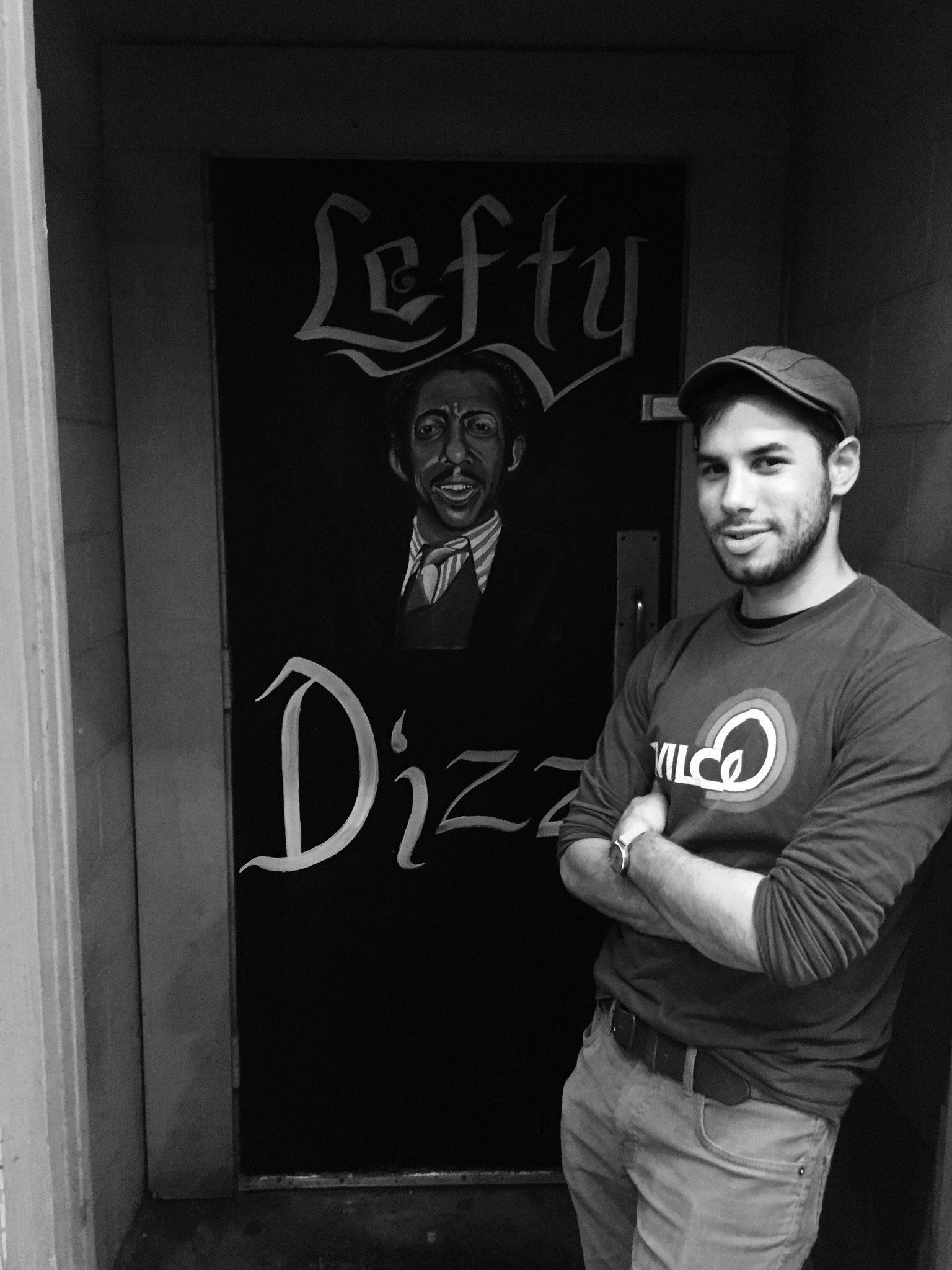 A man is standing in front of a door that says lefty dizzy.