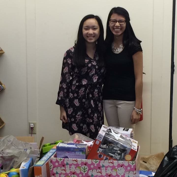 Two women are posing for a picture in front of a box of toys