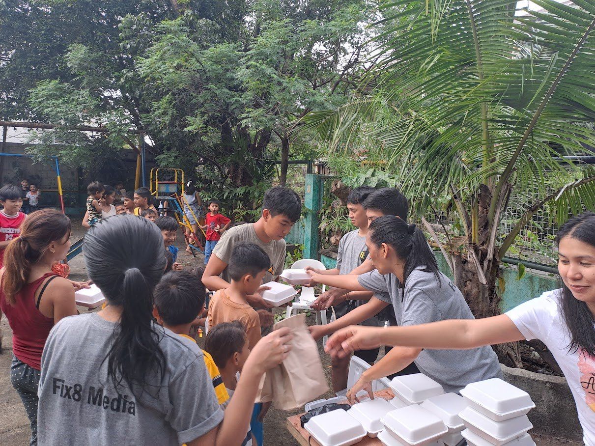 A group of people are standing around a table holding styrofoam containers.