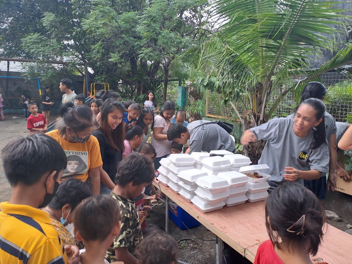 A group of people are standing around a table eating food.