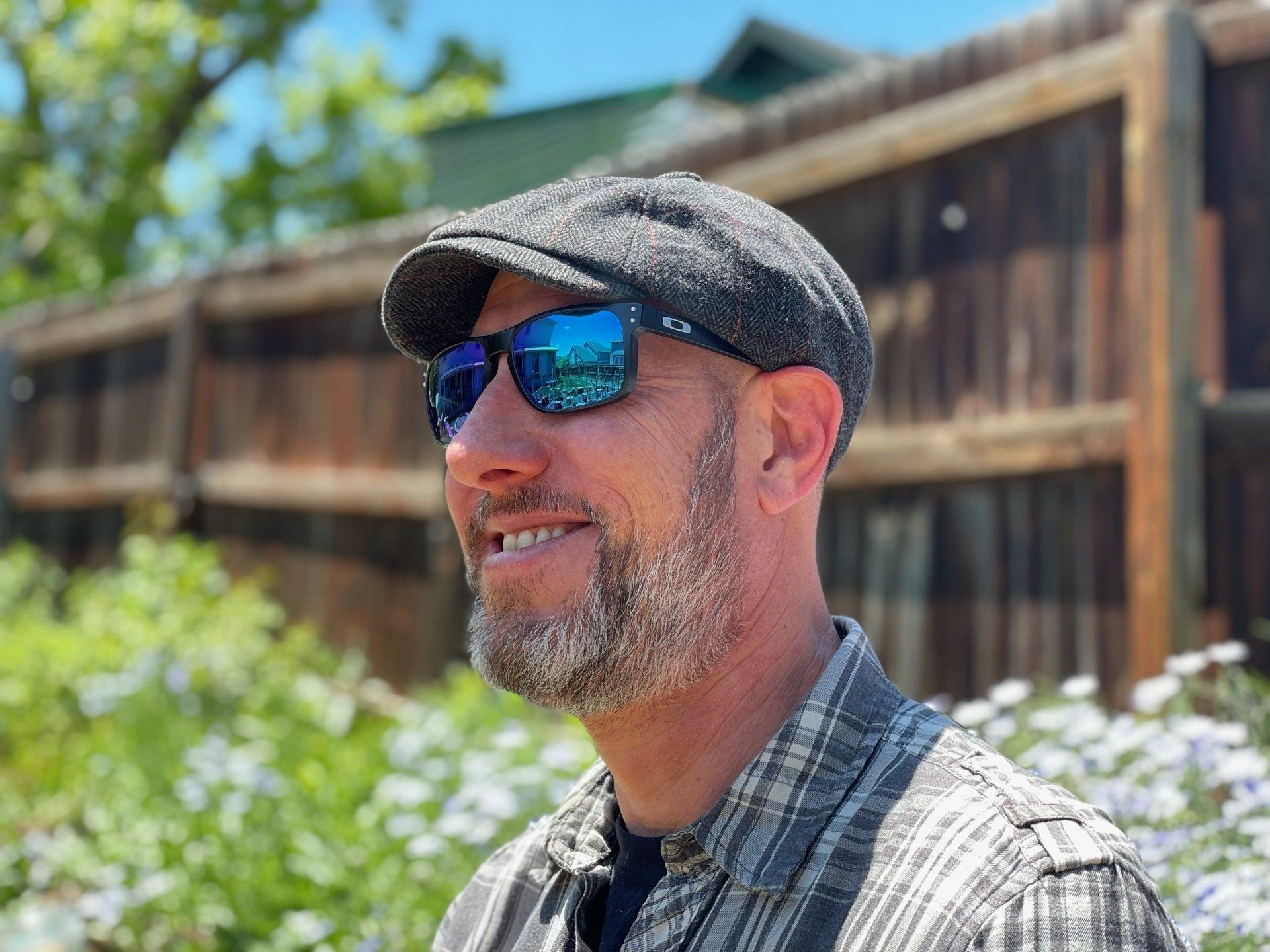 A man wearing sunglasses and a hat is standing in front of a building.