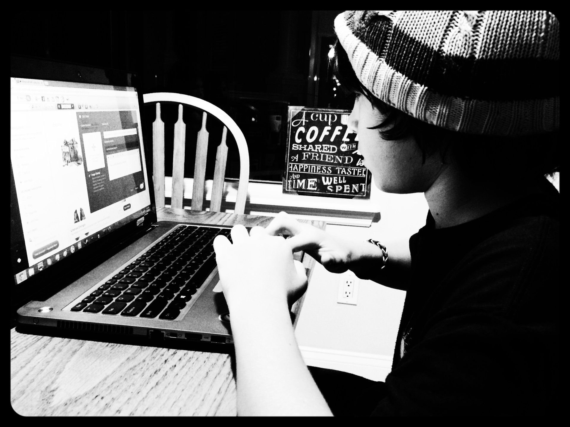 A person is typing on a laptop next to a sign that says coffee