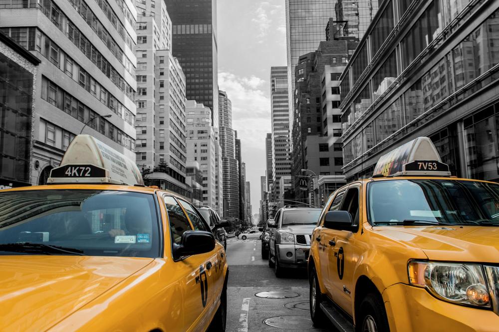 Two yellow taxis are parked on the side of a city street.