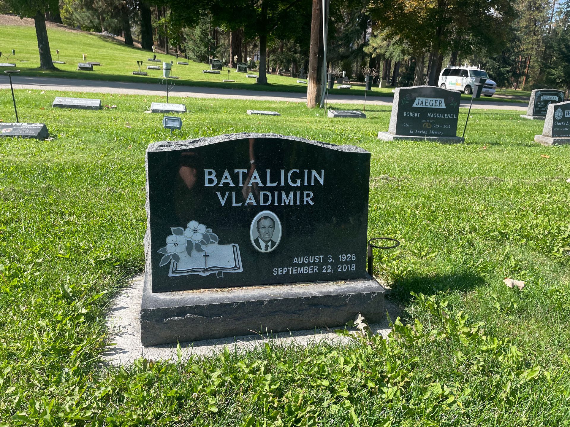 A black gravestone in a cemetery that says bataligin vladimir
