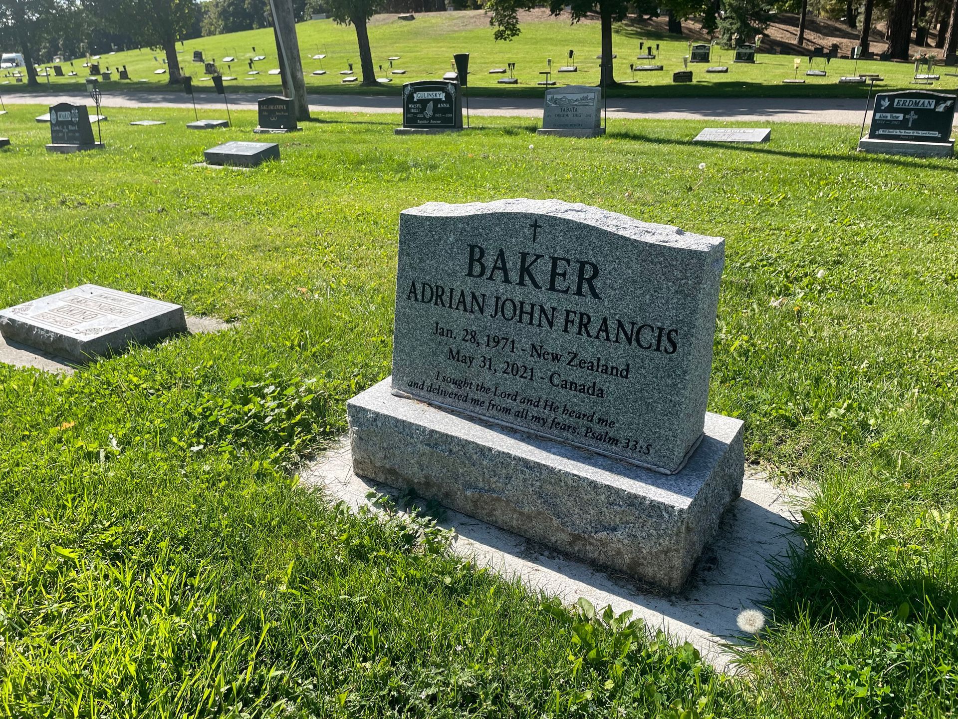 A gravestone for baker adrian john francis is in a cemetery.