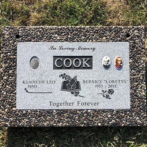A gravestone for a man named cook is sitting in the grass.