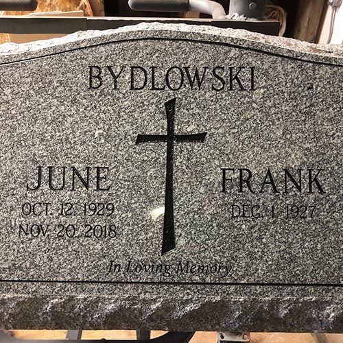 A gravestone for a couple of people with a cross on it.