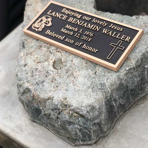 A bronze plaque is sitting on top of a large rock.
