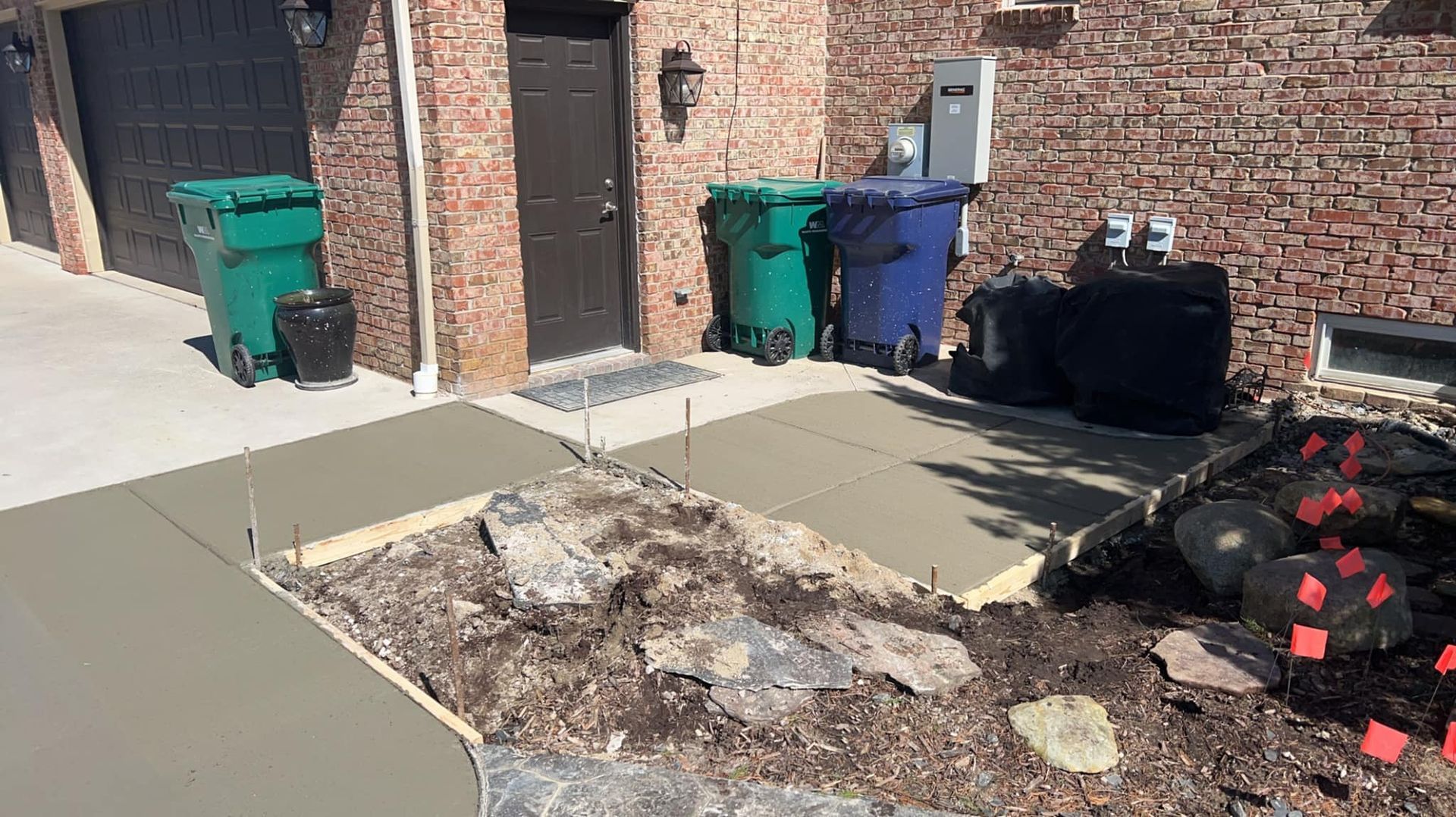 A concrete walkway is being built in front of a brick house.
