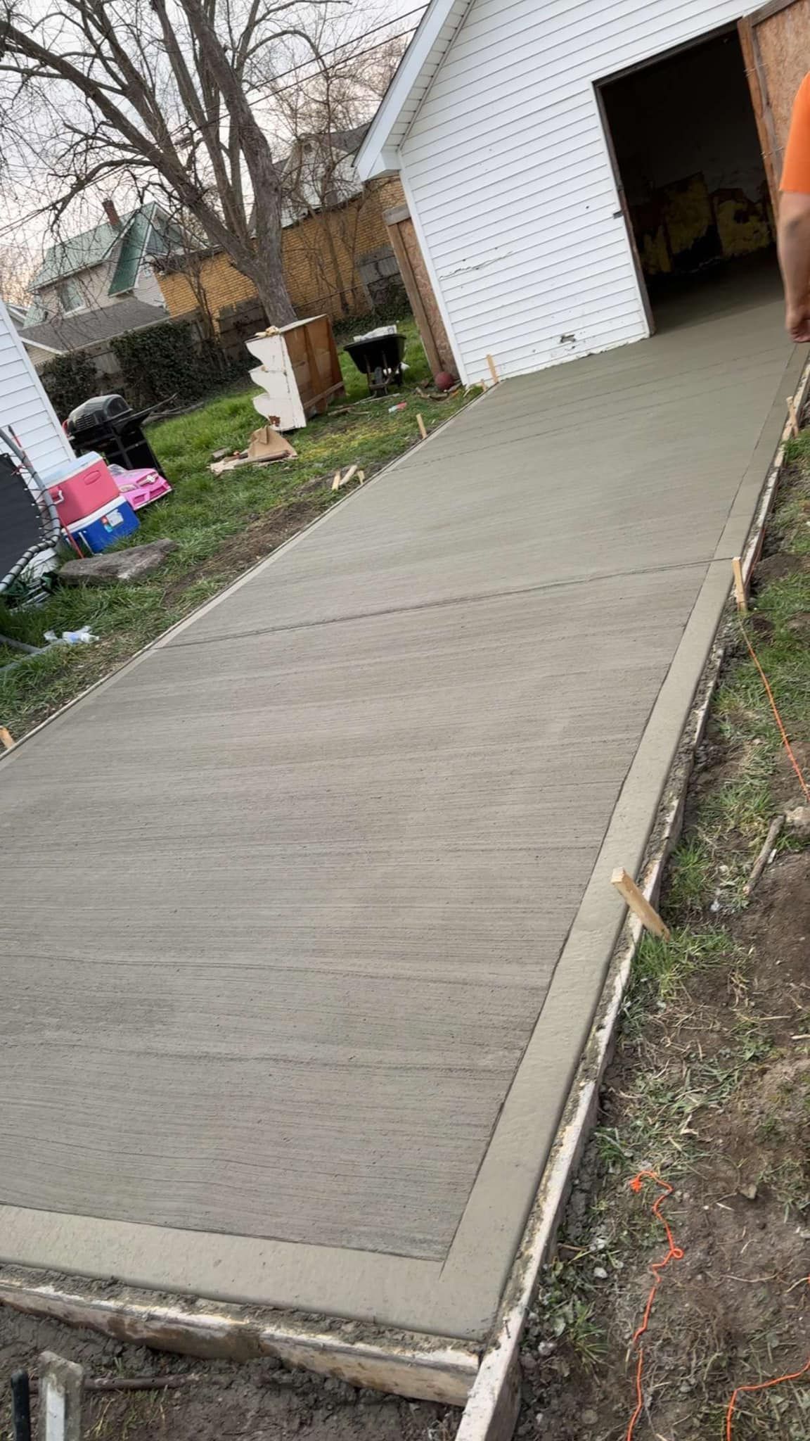 A concrete walkway is being built in front of a garage.