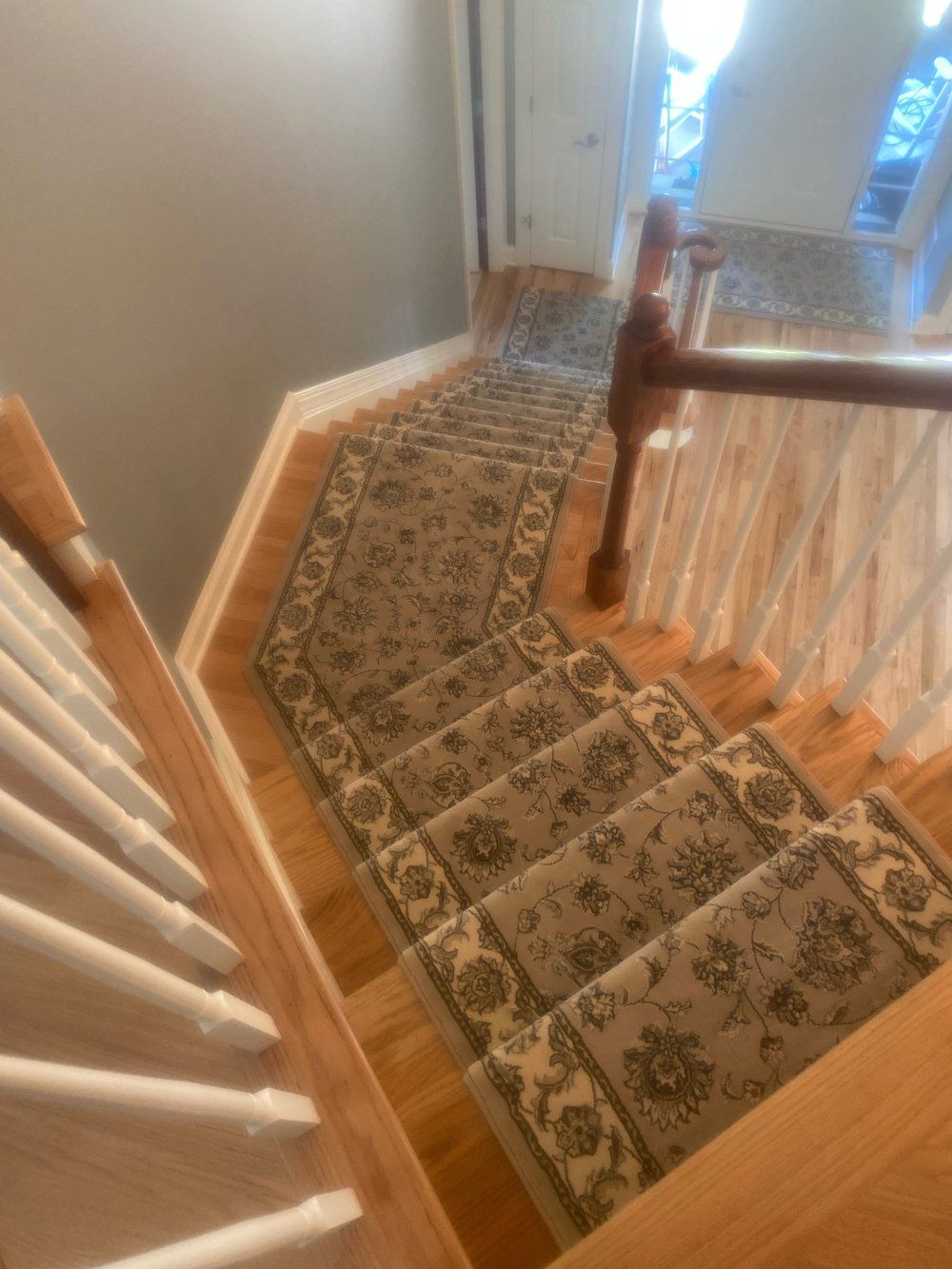 A wooden staircase with a rug on the stairs