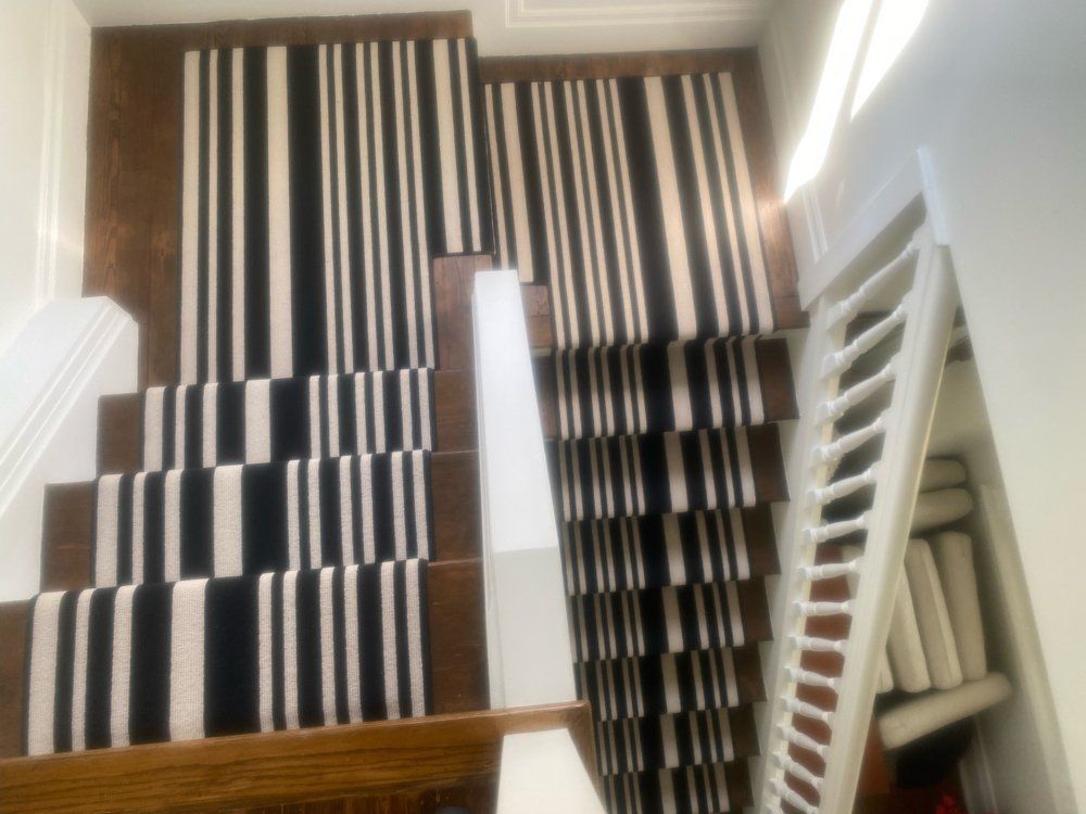 A staircase with a black and white striped carpet