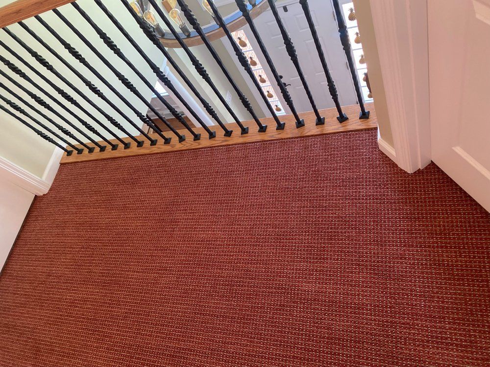 A staircase with a red carpet and a black railing
