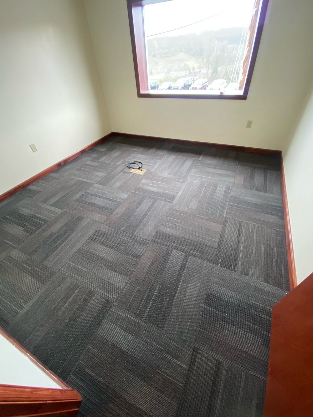 An empty room with a carpeted floor and a window