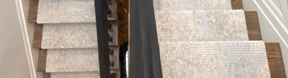 A close up of a staircase with a black railing and a carpeted staircase.