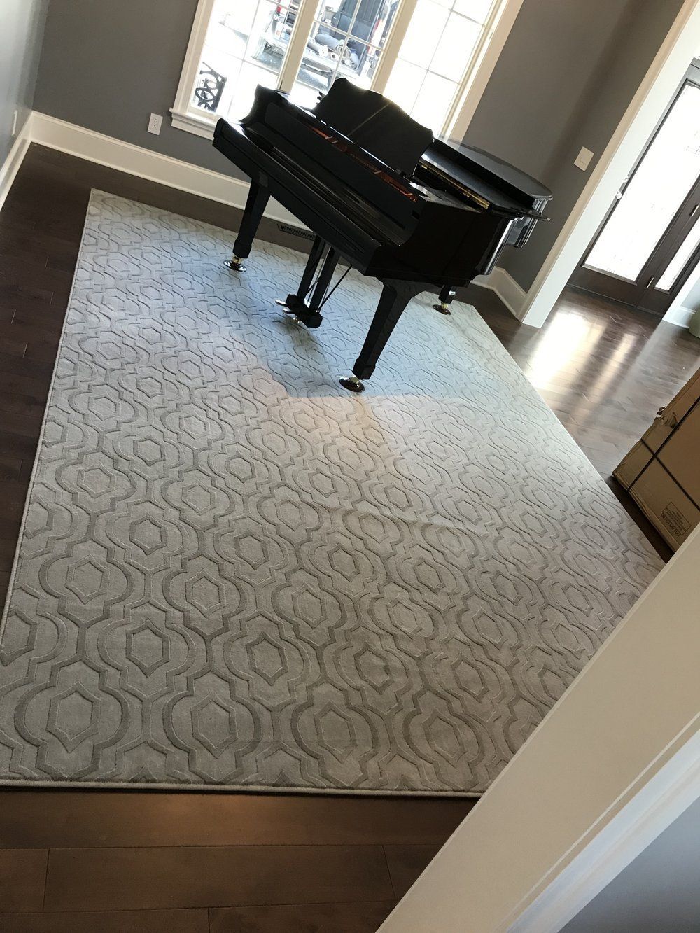 A piano is sitting on a rug in a living room.